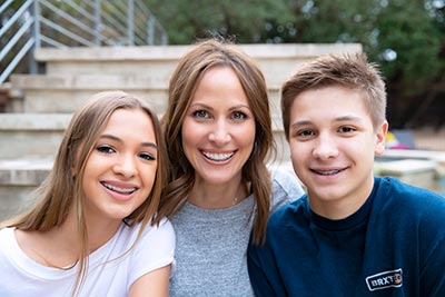 daughter and son smiling with their mom after getting braces at Smiles of Austin